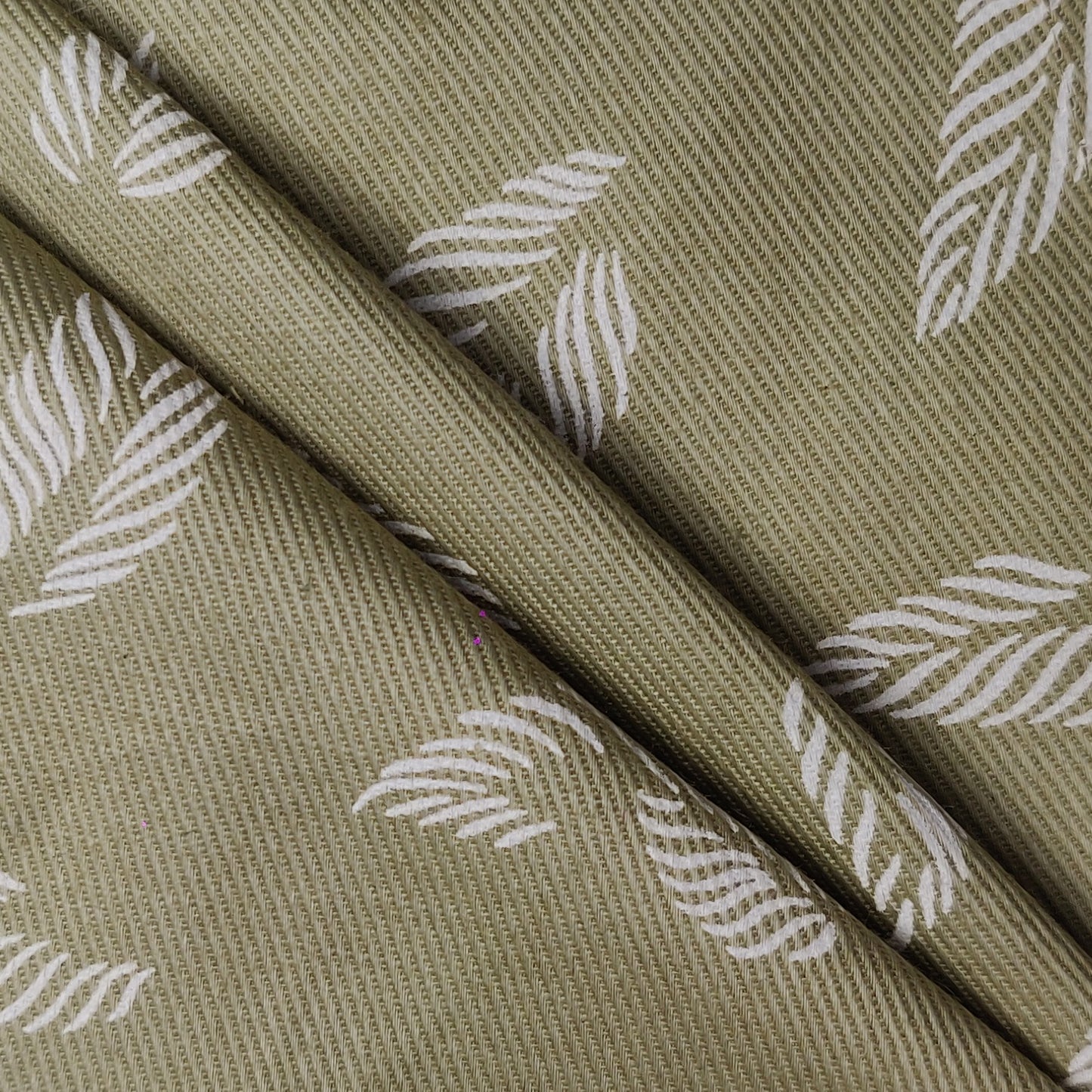 unstitched fabric with white leaf pattern on a green background